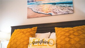 Un lit avec deux oreillers de couleur jaune moutarde et un oreiller sur lequel est écrit le mot « soleil ».