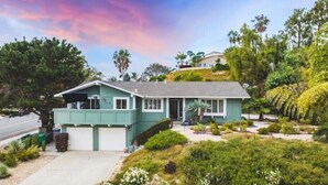 Une maison de plain-pied avec un garage, entourée d’un jardin aménagé avec différentes plantes et arbustes.
