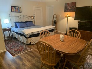 Een slaapkamer met een bed, nachtkastje, lamp en een televisie.