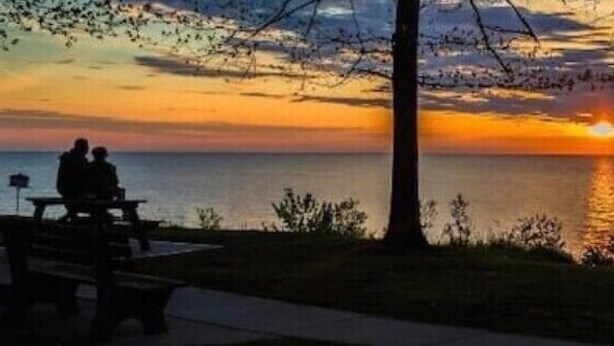 A sunset view from a park bench overlooking a body of water.