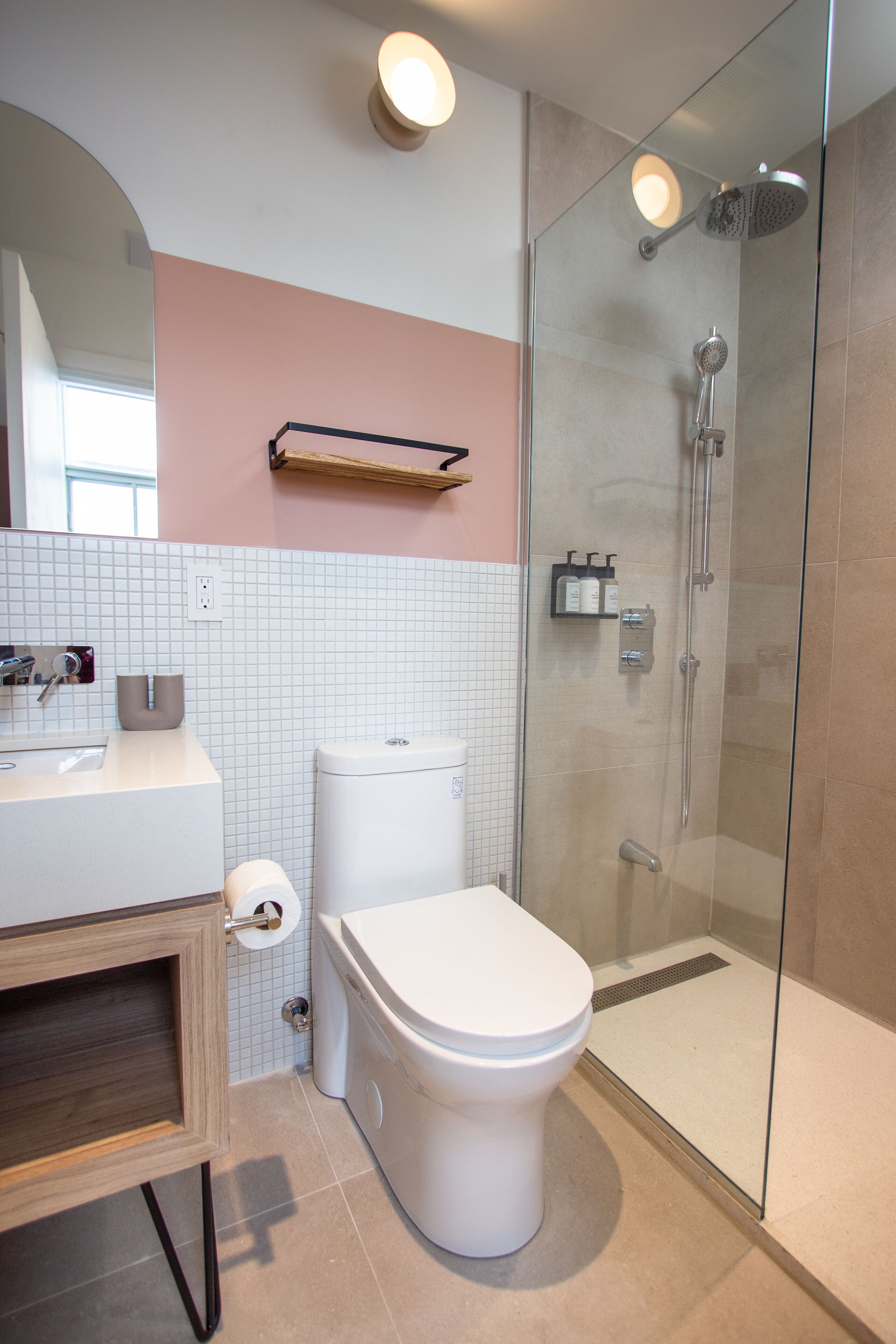 Un baño moderno con inodoro, lavabo y ducha con mampara de vidrio.