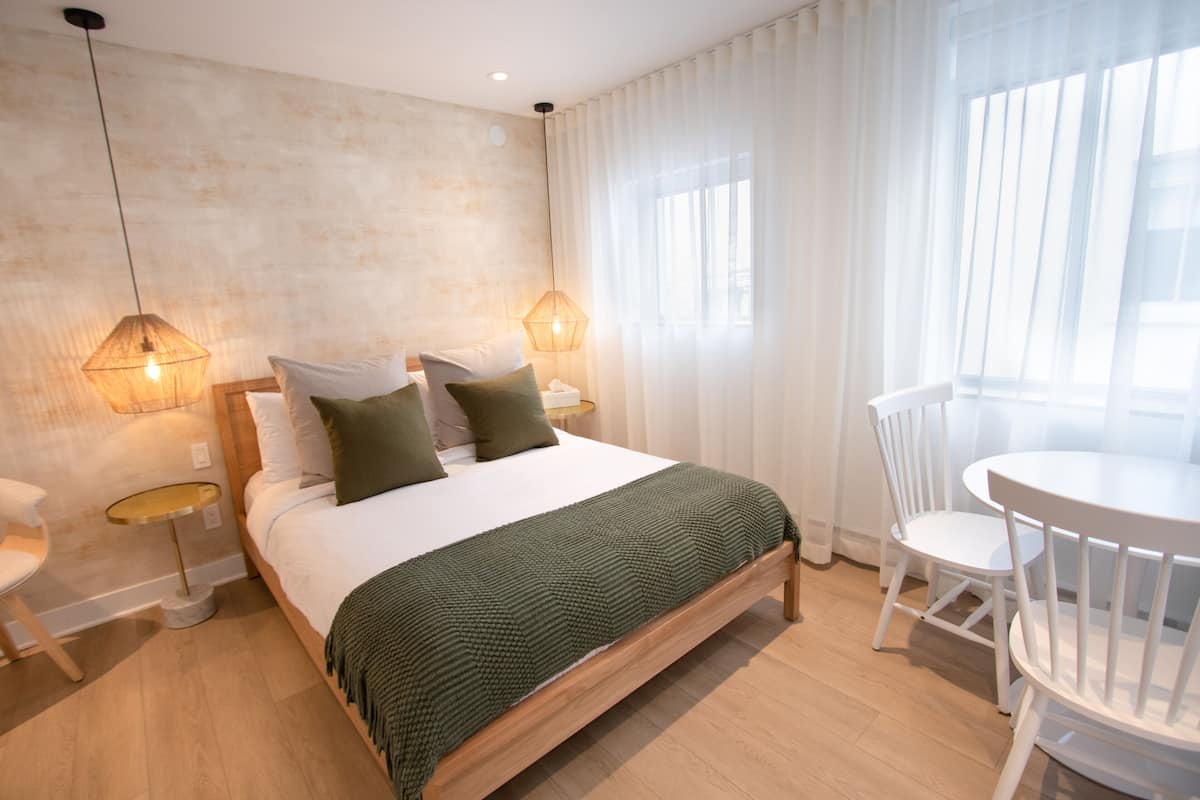 A neatly arranged bedroom with a bed, bedside tables, a chair, and a small table.