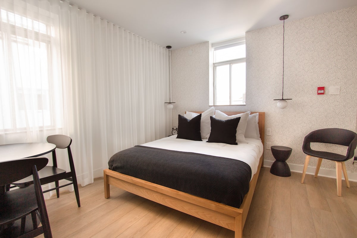A modern bedroom with a wooden bed, a desk, and a chair.