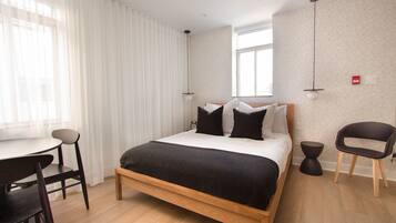 A modern bedroom with a wooden bed, a desk, and a chair.