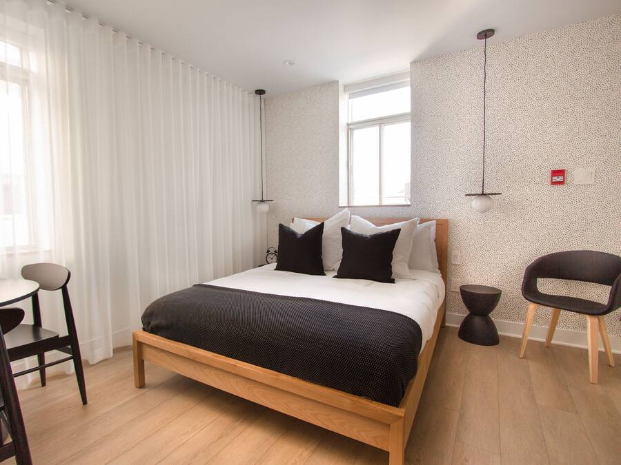 A modern bedroom with a wooden bed, a desk, and a chair.