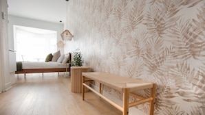 A bedroom with a bed, a bench, a small table, and a potted plant. - Unique Stays - 4119 St-Denis (Montreal)