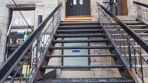 A set of metal stairs leading to a building entrance with a black door and a small light above it. - Unique Stays - 4119 St-Denis (Montreal)