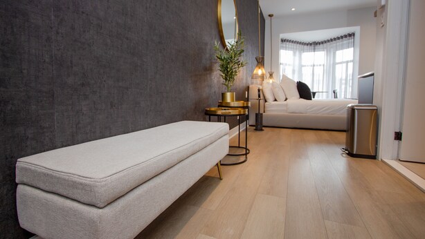 A modern bedroom with a large bed, bedside tables, a mirror, and a potted plant. - Unique Stays - 4119 St-Denis (Montreal)