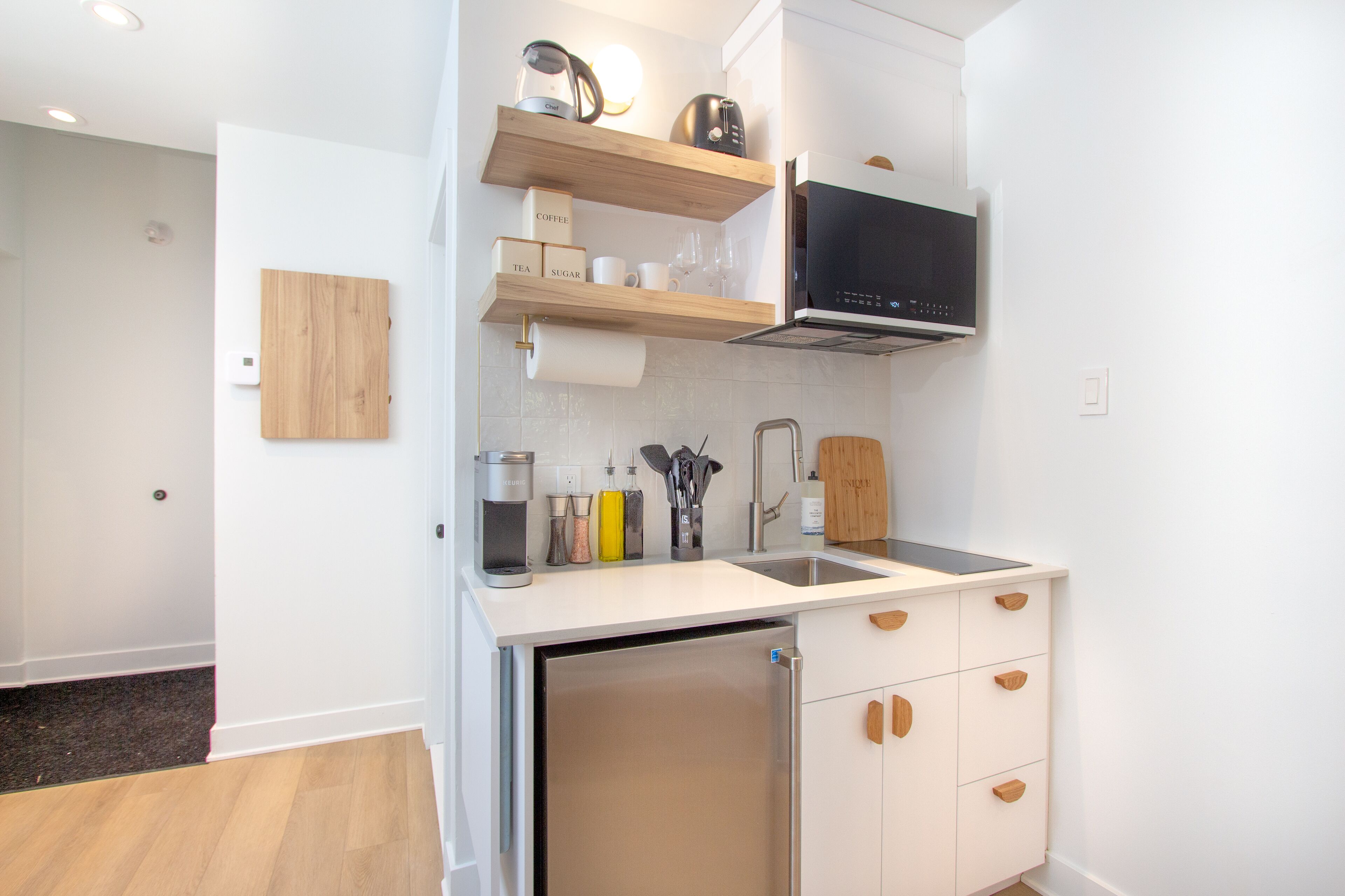 A modern kitchen with a built-in dishwasher, wooden cabinets, and a microwave.