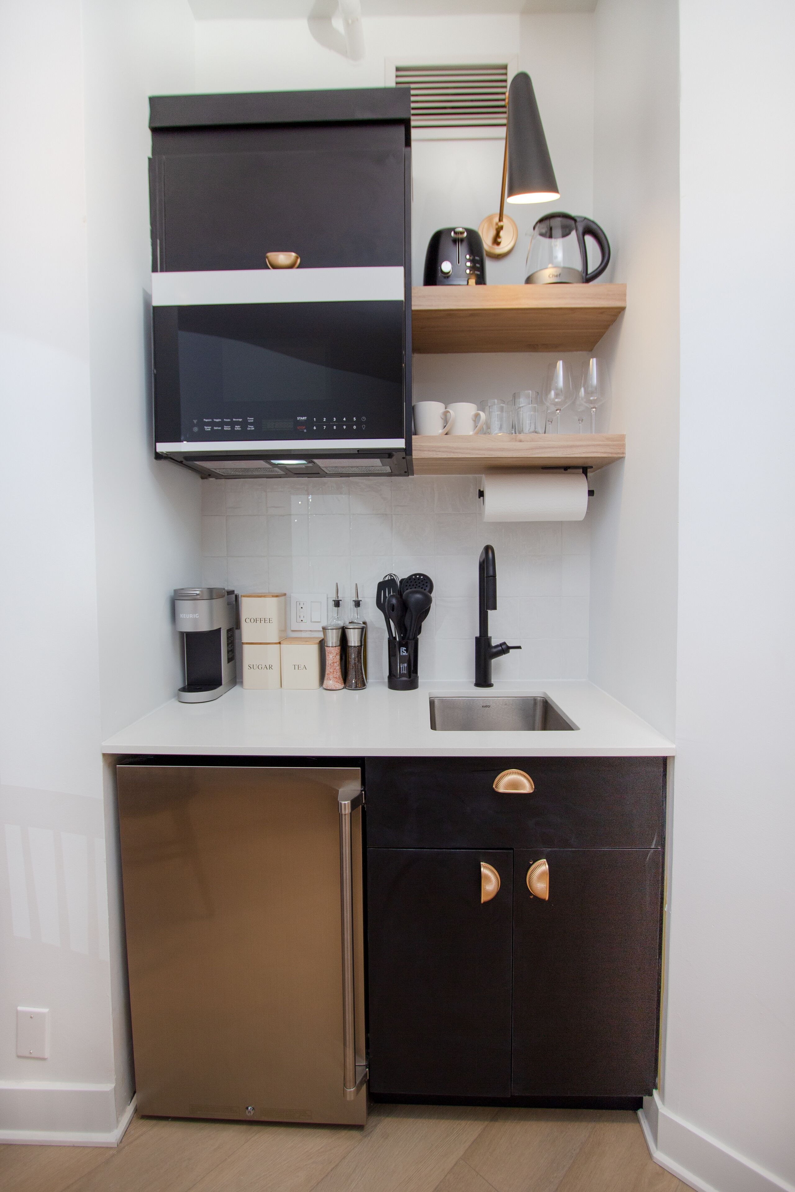 A compact kitchen with a built-in microwave, coffee maker, and a sink.