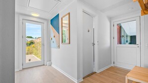 A hallway with a wooden floor, white walls, and a door with a window.
