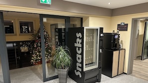 A snack vending machine labeled "Snacks" in a hotel lobby with a Christmas tree and a potted plant. - Aparthotel Rotheul (Föritztal)