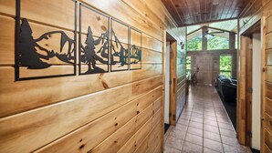 A wooden interior hallway with a mountain-themed wall art, wooden paneling, and a tiled floor. - Serene Wooded Family Mtn. Cabin- Great Location next to everything- Pet Friendly (Pigeon Forge)