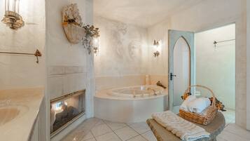 Relax in a spacious bathroom with a bathtub, fireplace, and decorative mirror.