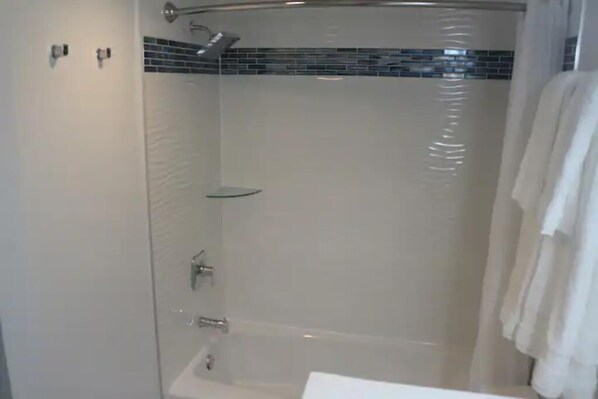 Un baño moderno con cabina de ducha de vidrio, un lavamanos blanco y un perchero para toallas.