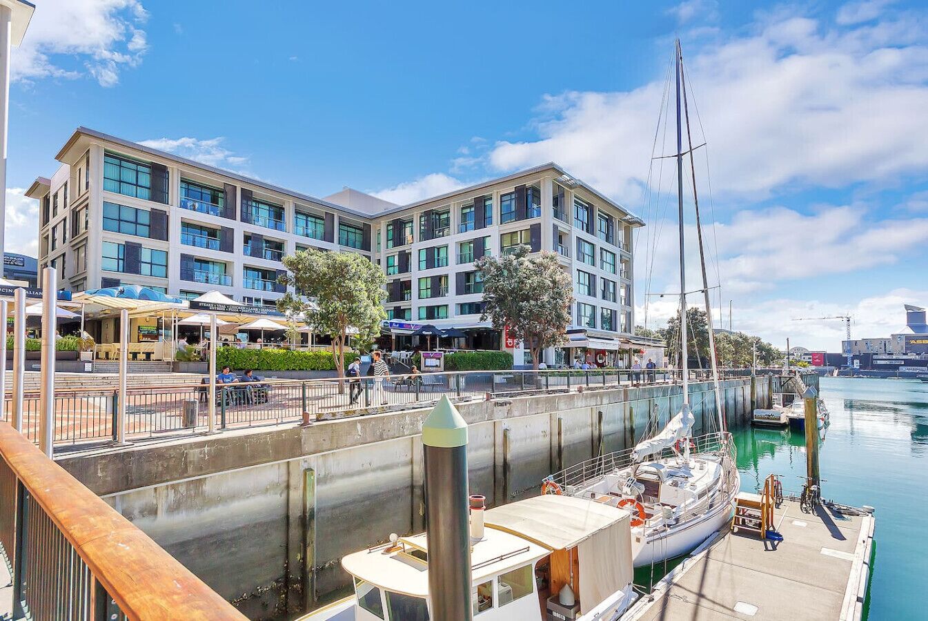 A waterfront hotel with a marina, outdoor seating, and a modern building facade.