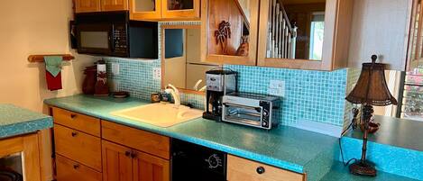 A kitchen with wooden cabinets, a microwave, a toaster, and a sink.