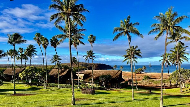 Ein tropisches Resort mit Palmen, einem Strand und Blick auf den Ozean.