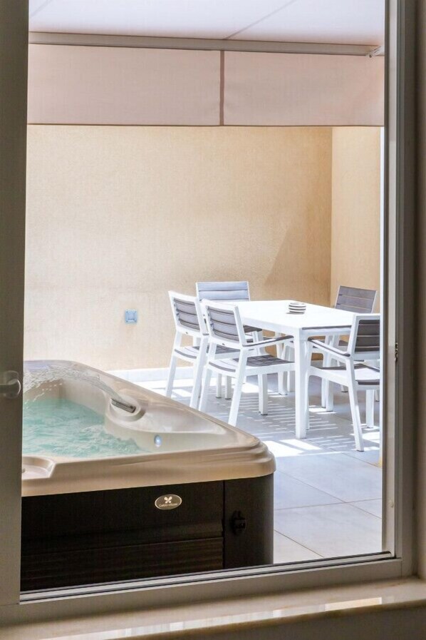 Een hottub en een tafel met stoelen in een zonnig buitengebied.