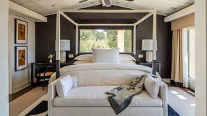 A four-poster bed with a view of greenery outside, a white sofa, and two bedside tables with lamps. - Sttupa Estate Napa Valley (Napa)