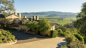 A large house with a driveway, surrounded by trees and hills in the background. - Sttupa Estate Napa Valley (Napa)