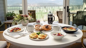 A breakfast table with various dishes, a coffee pot, and a view of the outdoors. - Sttupa Estate Napa Valley (Napa)