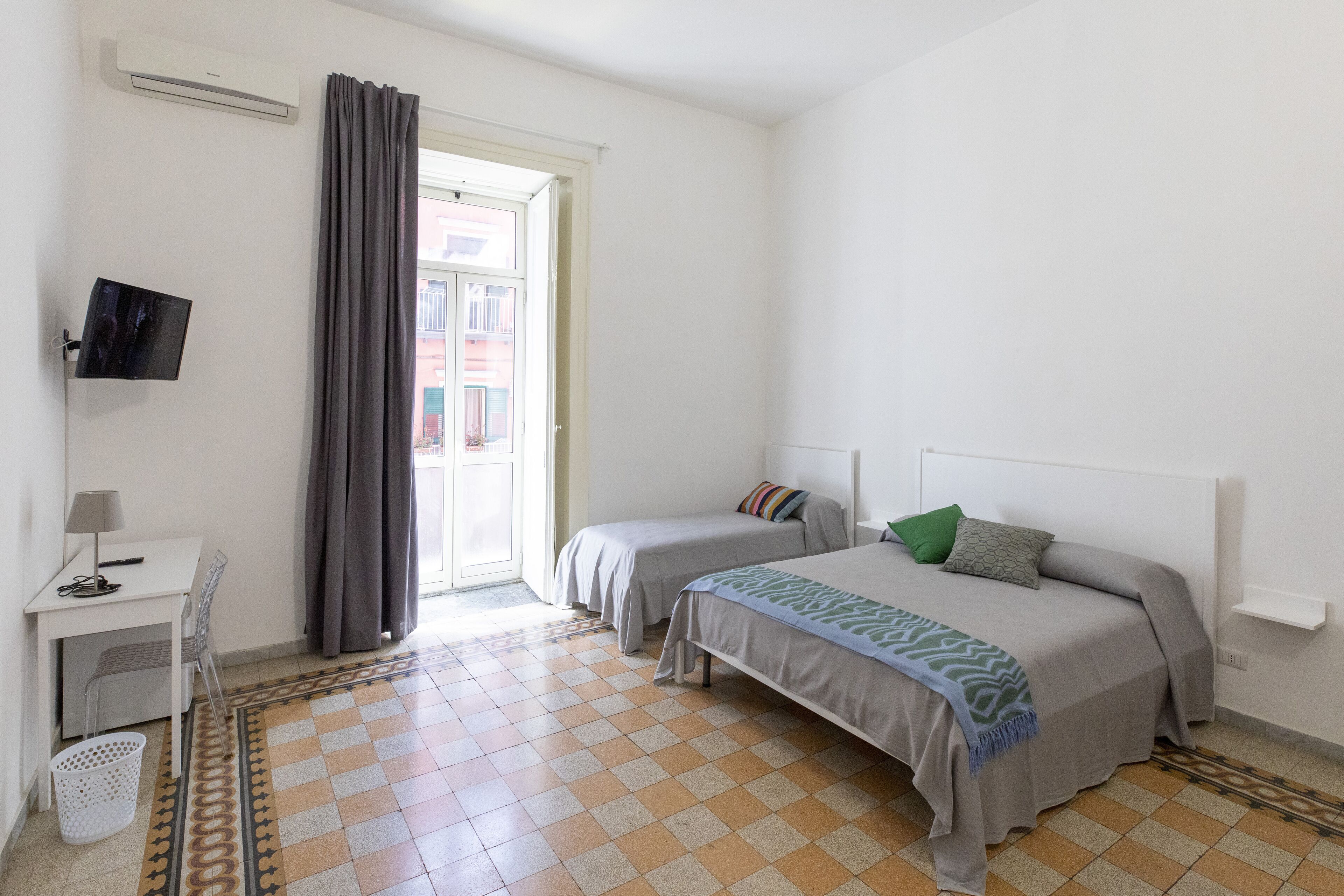 A bedroom with a bed, a desk, a chair, and a TV.