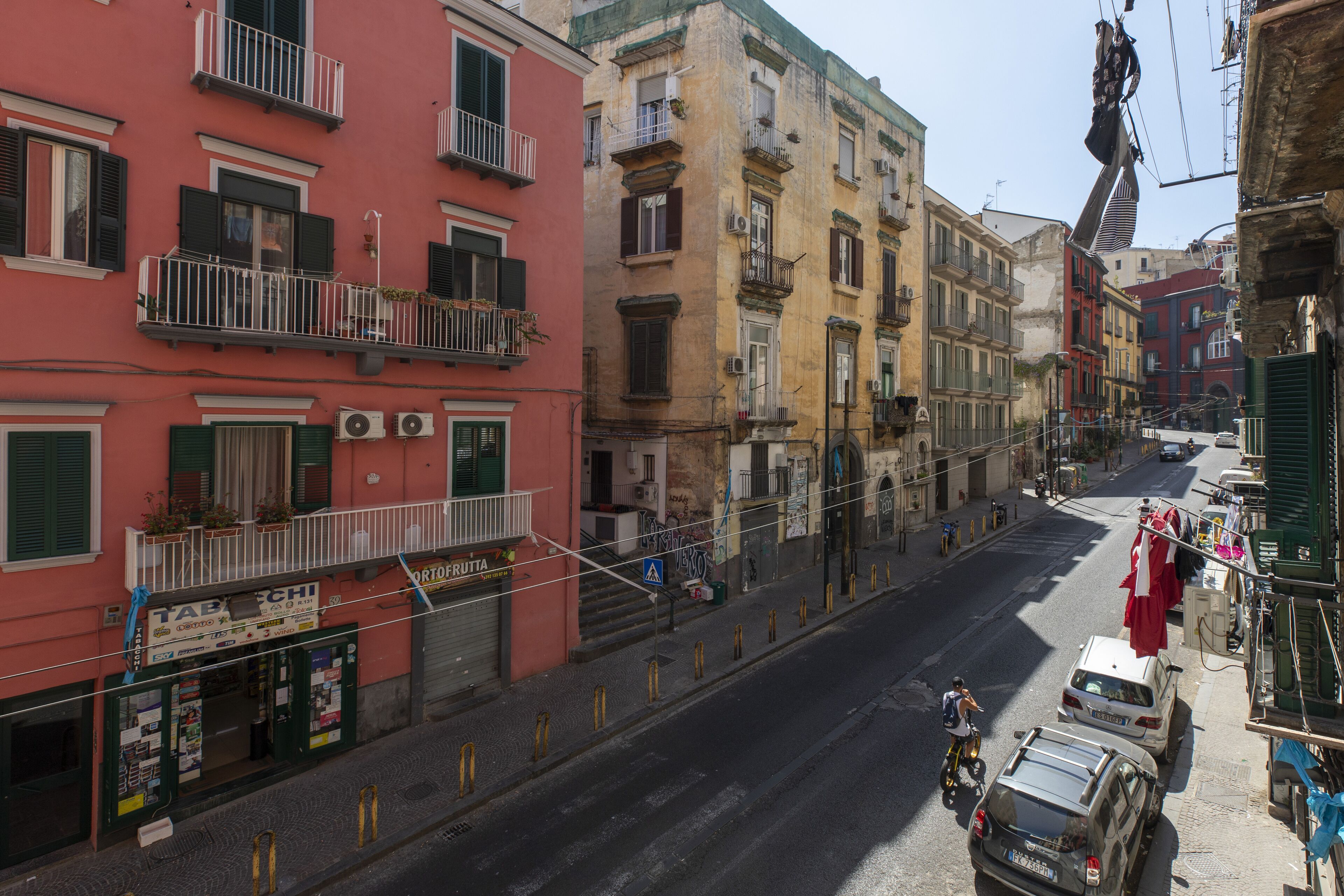 A street view with buildings, a parked car, and a motorcycle.