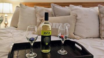 Una cama con un atril que sostiene una botella de sauvignon blanc, dos copas y un pequeño recipiente con chocolate.