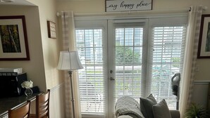 Ein Wohnzimmer mit einer Couch, Sesseln, einem Couchtisch und einem Essbereich mit einer Lampe und einer Mikrowelle.