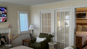 Ein Schlafzimmer mit zwei Betten, einem grünen Sessel, einem kleinen Tisch mit einer Lampe und einem Fernseher an der Wand.