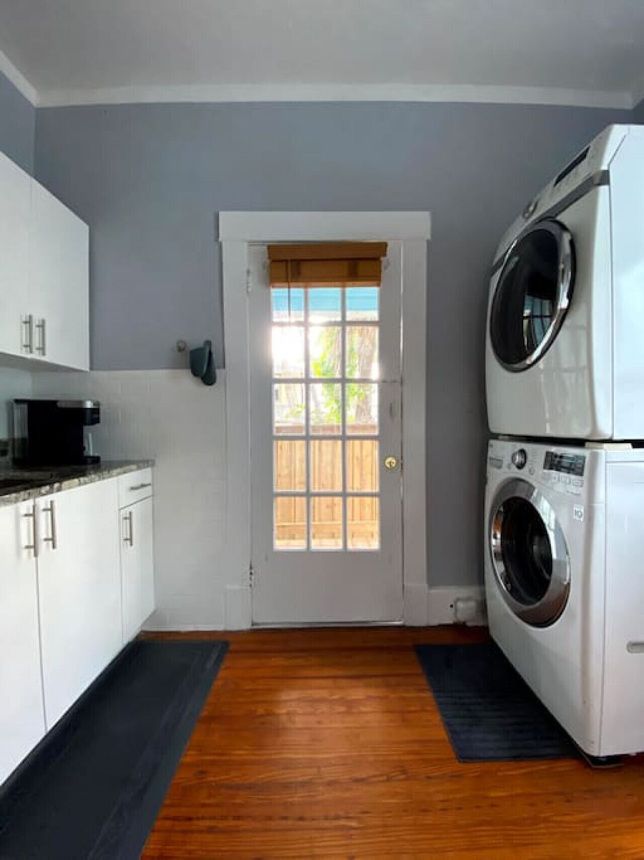 Une buanderie équipée d’un lave-linge et d’un sèche-linge, une porte avec une fenêtre et un plancher en bois.