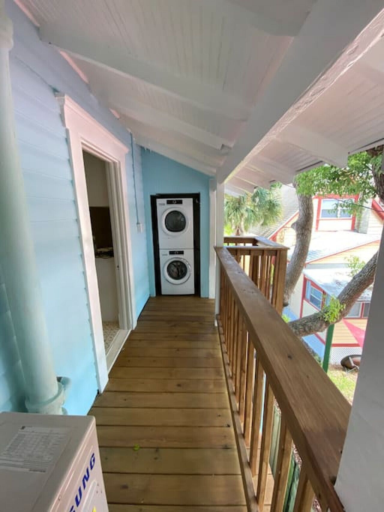 A wooden deck leading to a laundry room with a washing machine and dryer.