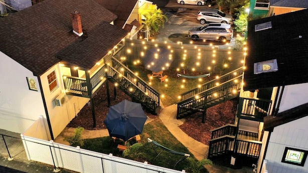 Une cour intérieure avec un escalier, des sièges extérieurs et des guirlandes lumineuses.