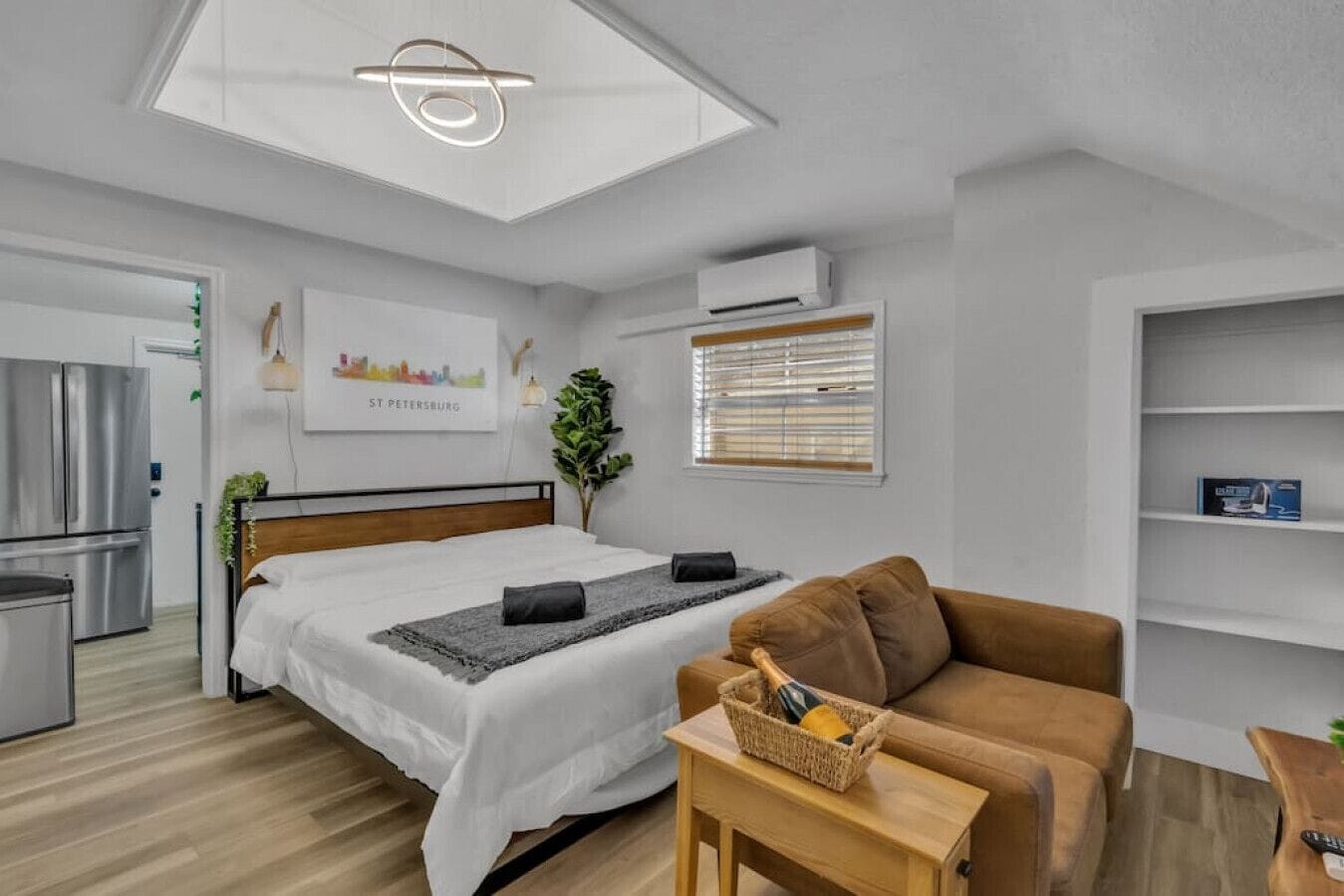 Ein modernes Hotelzimmer mit Bett, Sofa, kleinem Tisch, Pflanze und Stadtbild.