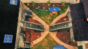 Vue aérienne d’une cour intérieure avec un espace de repos central, entouré de sentiers et de verdure.