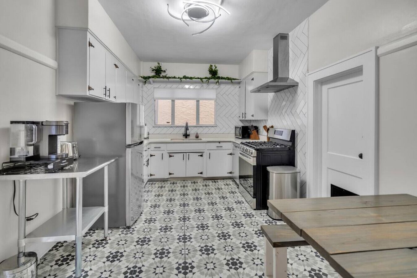 A modern kitchen with white cabinetry, a black stove, and a patterned floor.
