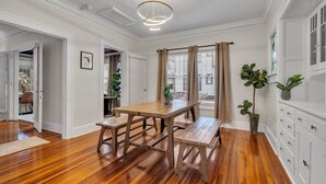 A dining area with a wooden table and benches, white walls, and a ceiling light fixture. - 436 WHOLE PROPERTY · Downtown Historic District Estate (Home + Cottage) (St. Petersburg)