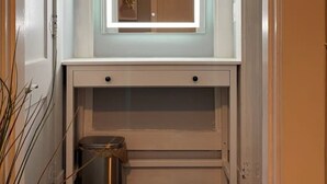 A narrow hallway with a recessed mirror above a door, a trash can, and a ceiling fan. - (1) 320 Unit #1 · Downtown St. Pete/Historic Old NE #1 (St. Petersburg)