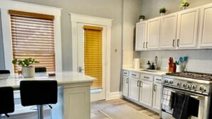 A modern kitchen with white cabinets, a central island, a stove, and a ceiling fan. - (1) 320 Unit #1 · Downtown St. Pete/Historic Old NE #1 (St. Petersburg)