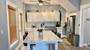 A modern kitchen with white cabinets, a central island, stainless steel appliances, and a ceiling fan. - (1) 320 Unit #1 · Downtown St. Pete/Historic Old NE #1 (St. Petersburg)