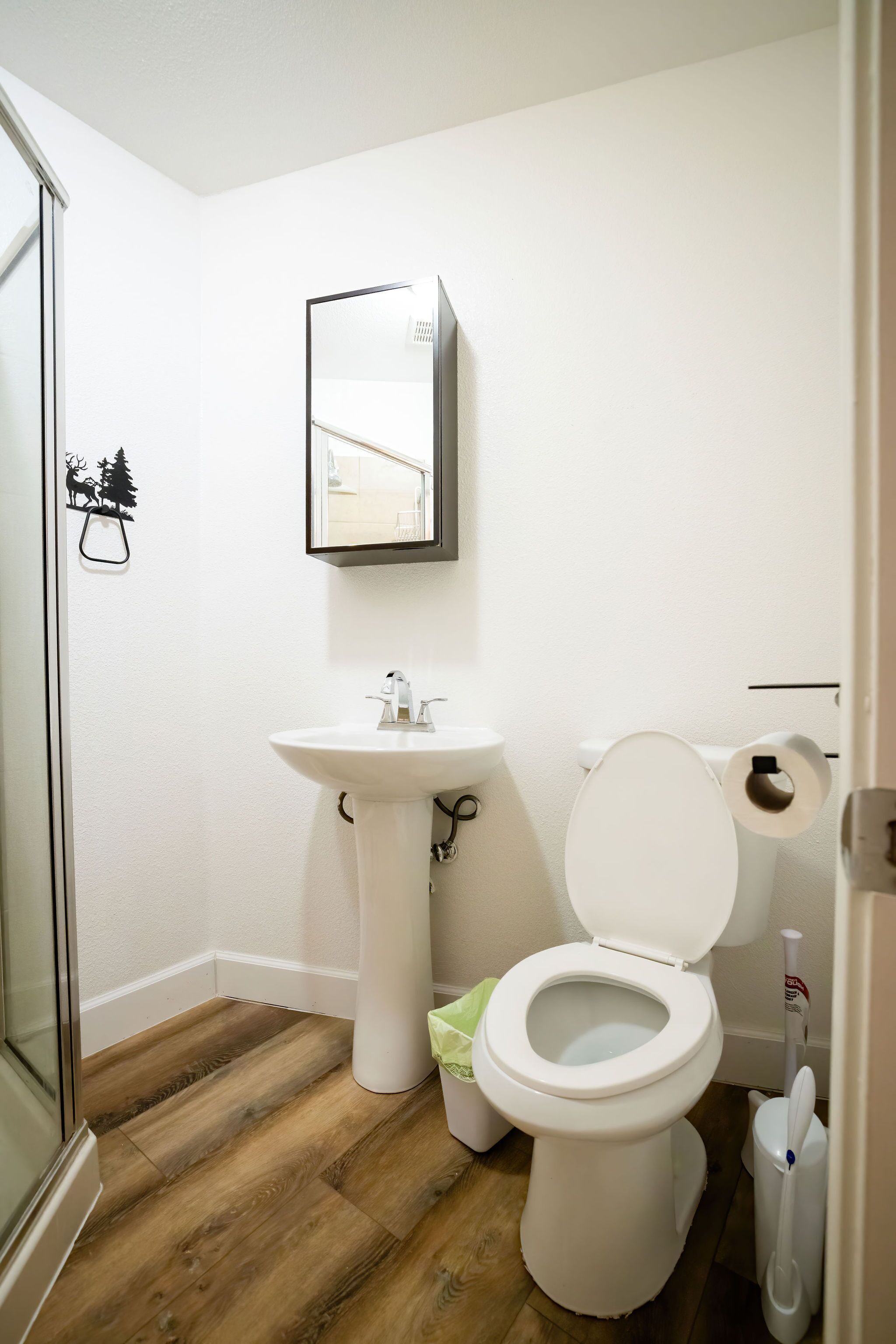A bathroom with a white sink, toilet, and a mirror above the sink.