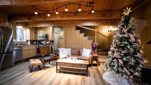 A cozy cabin interior with a wooden ceiling, a dining area with a wooden table and chairs, a kitchen with wooden cabinets, and a decorated Christmas tree. - Cozy retreat near Dodge Ridge Ski Resort, and Pinecrest Lake with fast Wi-Fi  (Cold Springs)