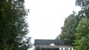 Eine Holzterrasse führt zu einem Haus mit schwarzem Dach und weißen Außenwänden.