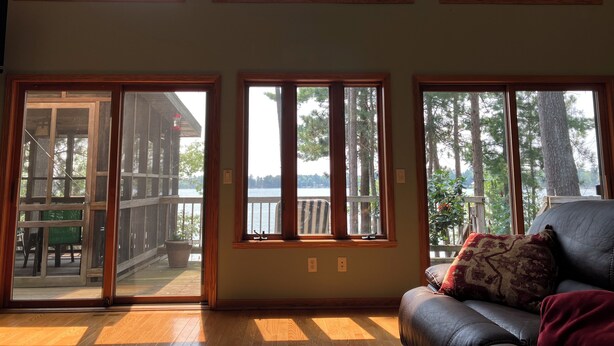 Ein Zimmer mit großen Fenstern, einer Holzterrasse und einem Ledersofa.