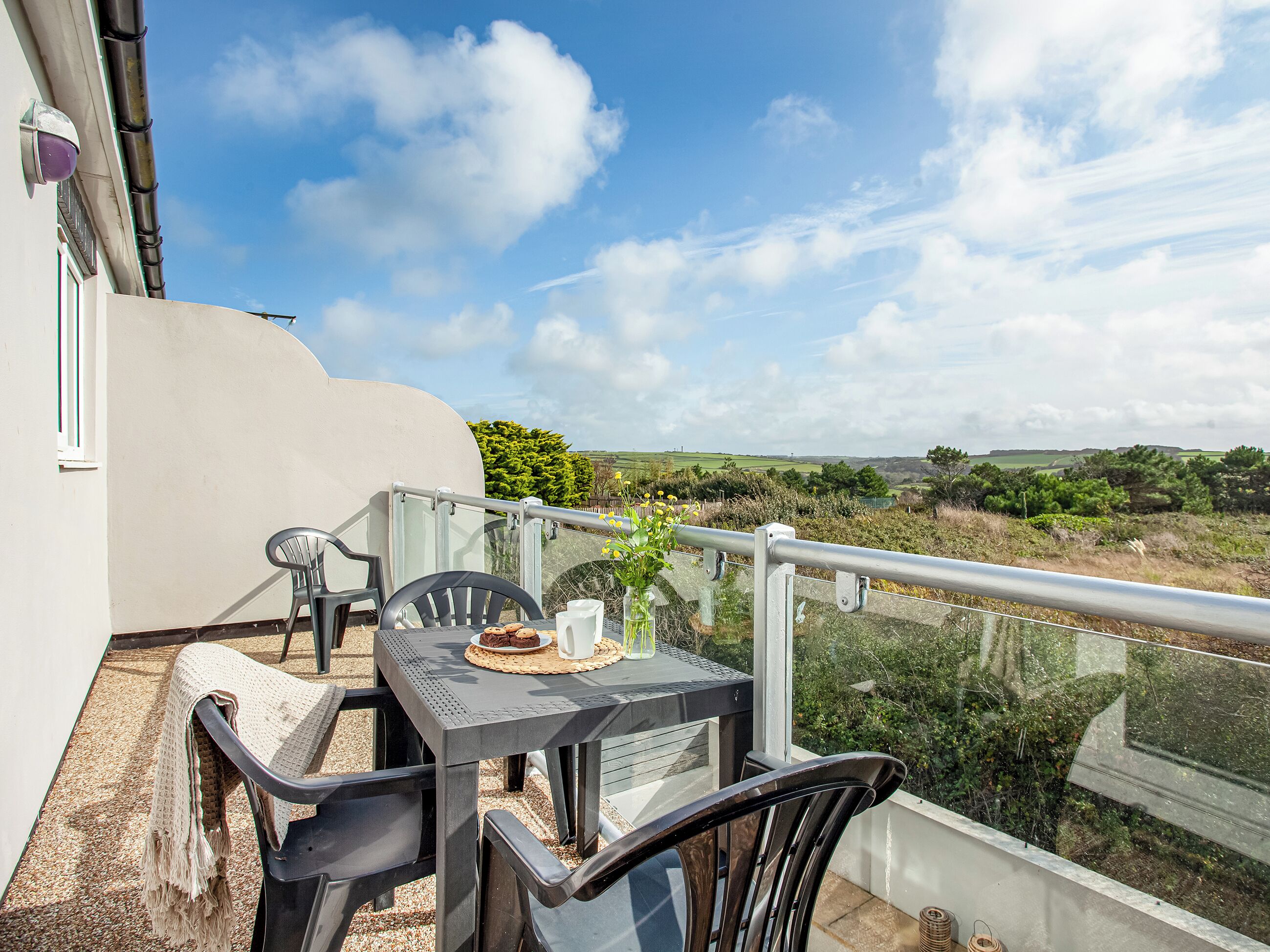 Ein Balkon mit Tisch, Stühlen und Blick ins Grüne.
