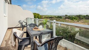 Un balcon avec une table, des chaises et une vue sur la campagne.