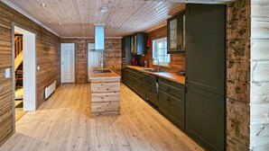 Eine moderne Küche mit Holzboden, eingebauten Schränken und einer zentralen Kochinsel.