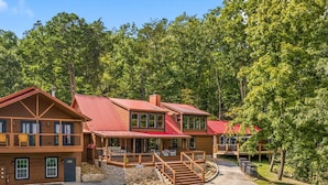 Un chalet à deux étages, doté d’un toit rouge, d’une façade en bois et de fondations en pierre.