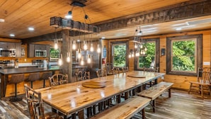 Une cuisine spacieuse dotée de meubles en bois, d’un îlot central avec des tabourets de bar et d’une grande table à manger avec des bancs.